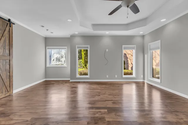 a view of an empty room with wooden floor and windows