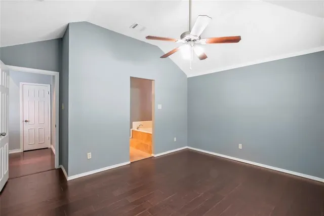 an empty room with wooden floor chandelier fan and windows
