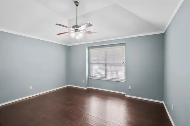 an empty room with wooden floor fan and windows