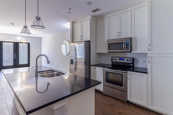a kitchen with stainless steel appliances granite countertop a sink a stove and white cabinets