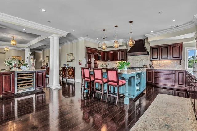 a open kitchen with stainless steel appliances kitchen island granite countertop a stove a refrigerator a dining table and chairs with wooden floor