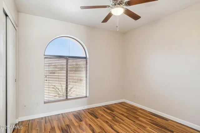 an empty room with a window and a ceiling fan