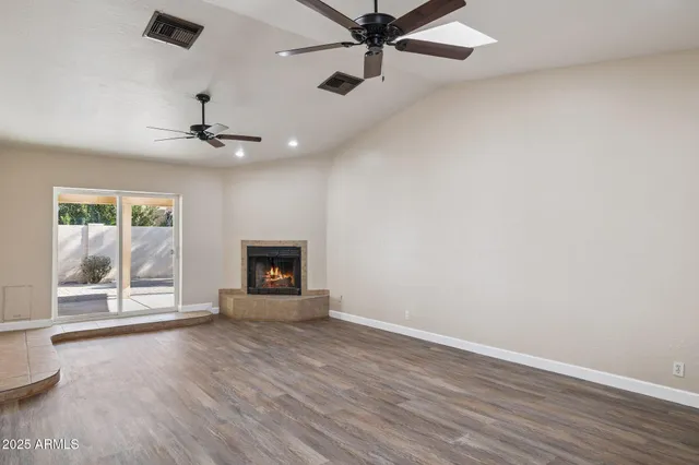 an empty room with windows fireplace and a ceiling fan
