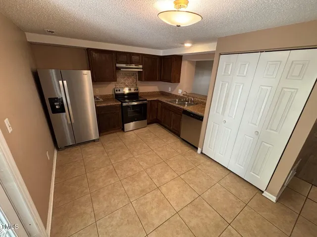 a kitchen with stainless steel appliances a stove a sink and a refrigerator
