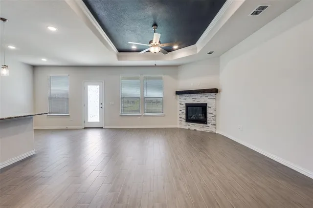 an empty room with wooden floor fireplace and windows