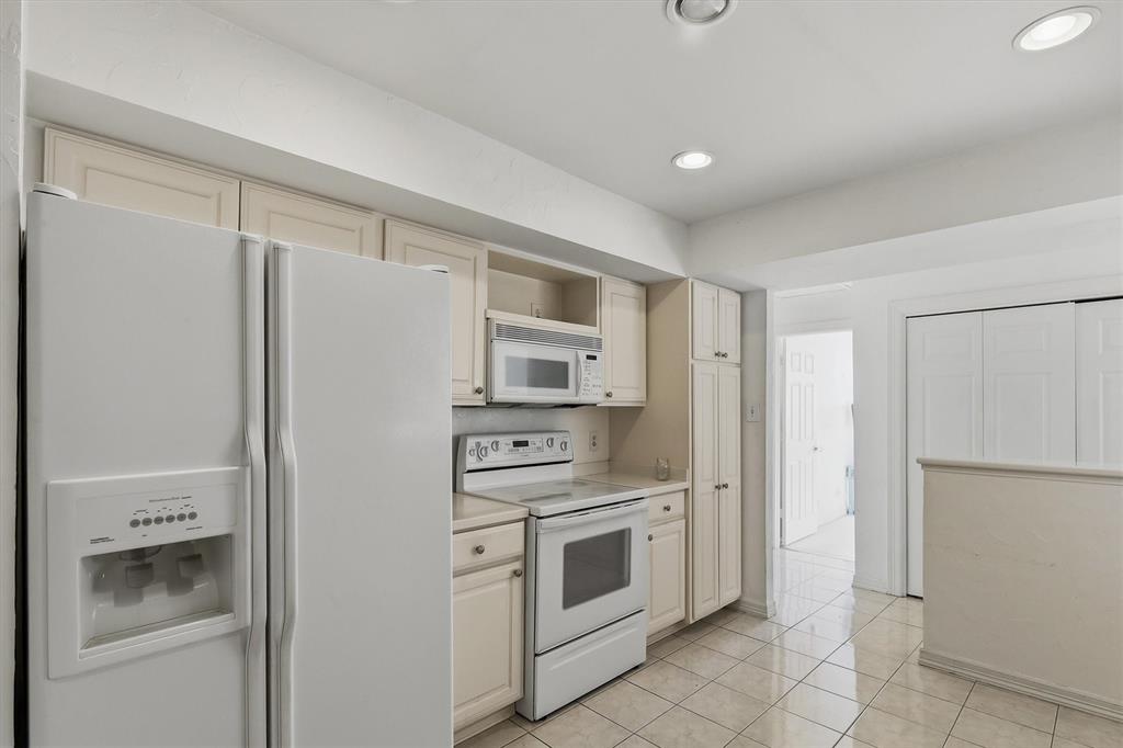 5200 Keller Springs Road, Unit 1315 Dallas, TX 75248 - Photo 7 of 40 a kitchen with white cabinets and white stainless steel appliances