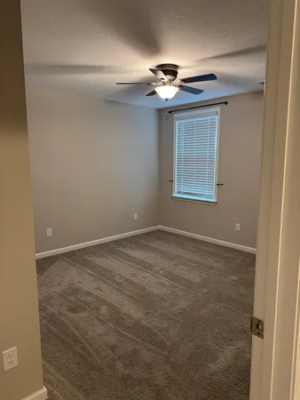 a view of an empty room with a chandelier fan