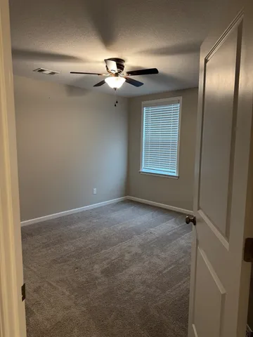 an empty room with windows and fan