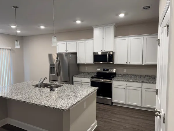 a kitchen with kitchen island granite countertop stainless steel appliances and wooden cabinets
