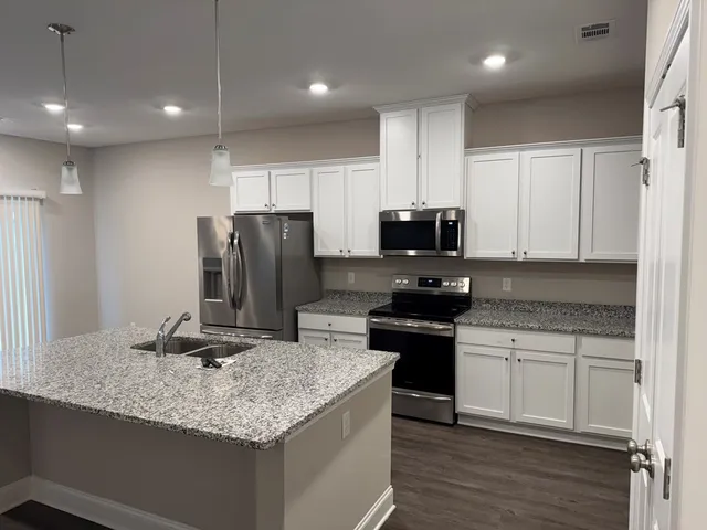 a kitchen with kitchen island granite countertop stainless steel appliances and wooden cabinets