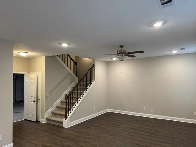 a view of an empty room with wooden floor and stairs