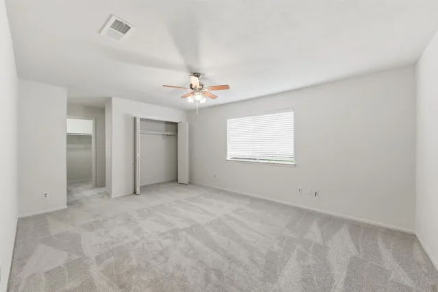 an empty room with windows and chandelier fan