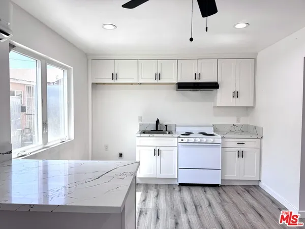 a kitchen with granite countertop white cabinets and white appliances