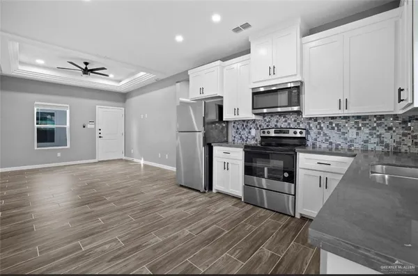 a kitchen with stainless steel appliances granite countertop a stove top oven a sink dishwasher and a refrigerator with wooden floor