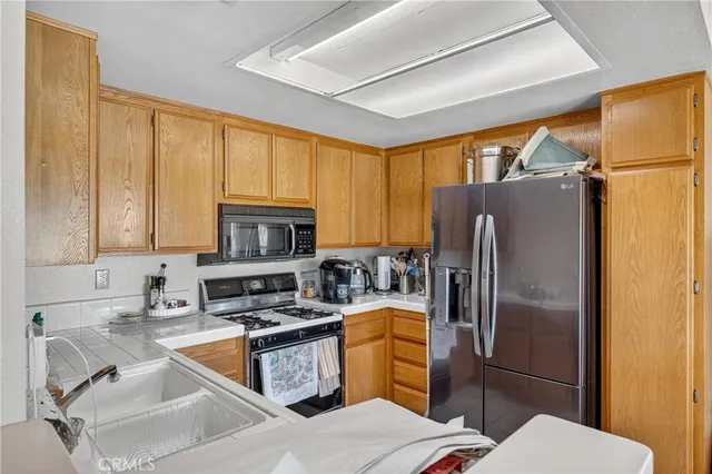 a kitchen with a refrigerator a sink stainless steel appliances cabinets and a counter top space