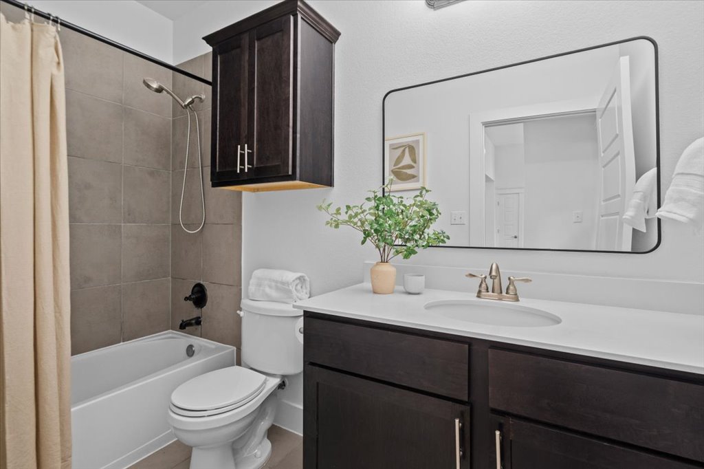 1765 Rowdy Loop, Unit 47 Leander, TX 78641 - Photo 31 of 40 Dark cabinetry and a tiled tub-shower combination anchor this clean bathroom design.