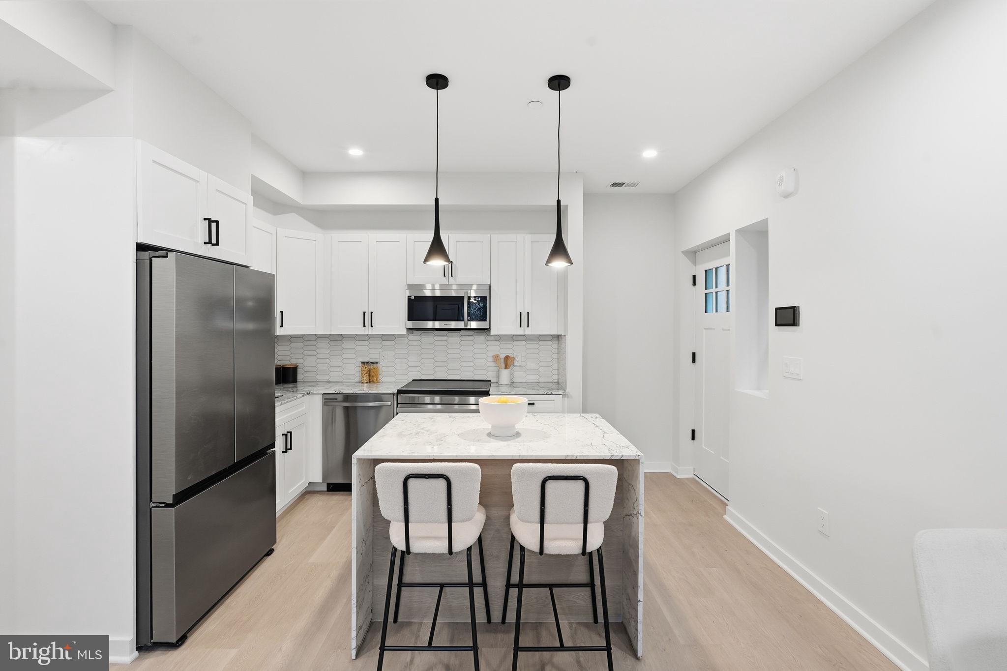 2606 41st Street Northwest, Unit 2 Washington, DC 20007 - Photo 5 of 26 a kitchen with stainless steel appliances a refrigerator a sink a stove a dining table and chairs