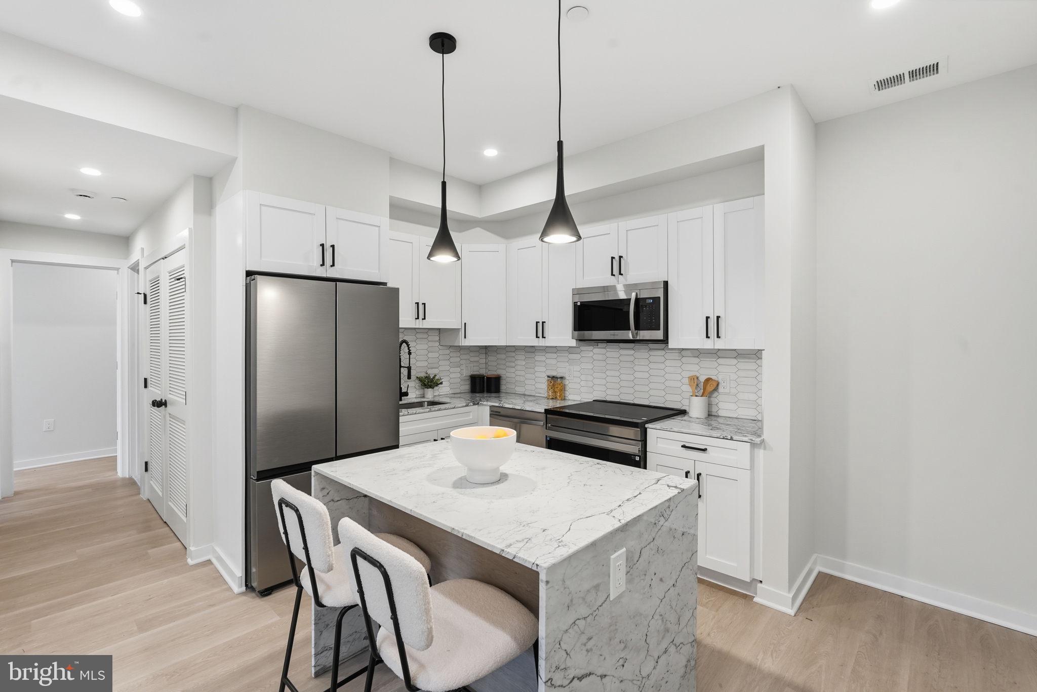 2606 41st Street Northwest, Unit 2 Washington, DC 20007 - Photo 6 of 26 a kitchen with stainless steel appliances kitchen island granite countertop a refrigerator a stove a microwave oven a sink with island and chairs