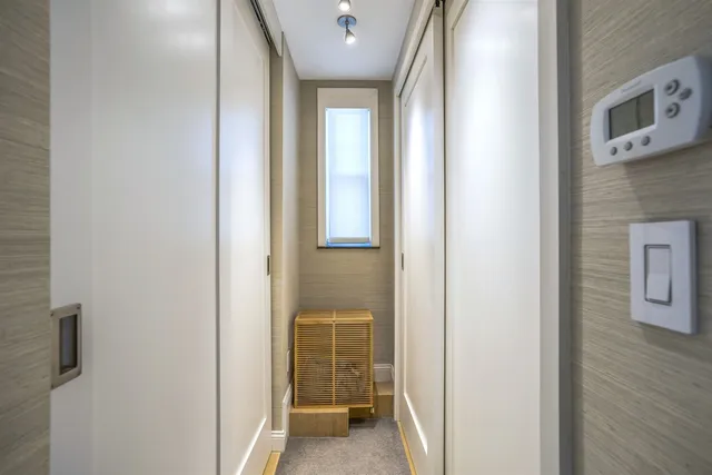 a view of a hallway with wooden floor and a bathroom