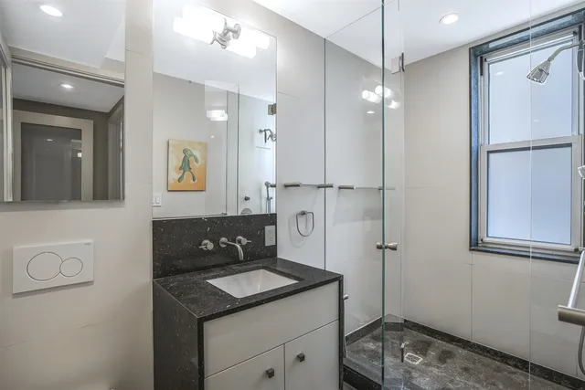 a bathroom with a granite countertop sink a mirror and shower