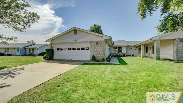 a view of a white house with a yard and table and chairs under an umbrella