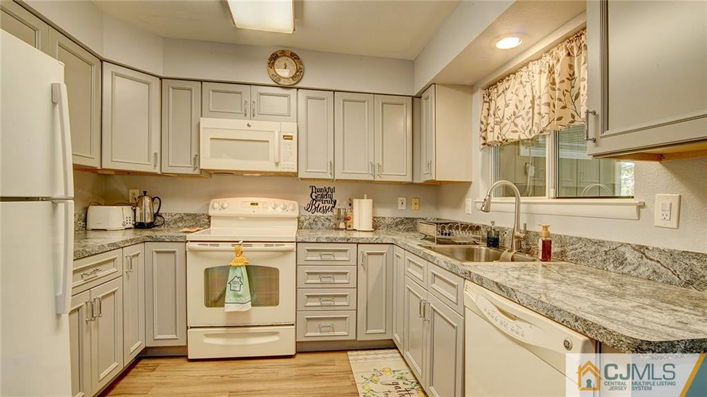 801 A Pompton Road, Unit 801A Monroe Township, NJ 08831 - Photo 11 of 33 a kitchen with stainless steel appliances granite countertop a sink and cabinets with wooden floor
