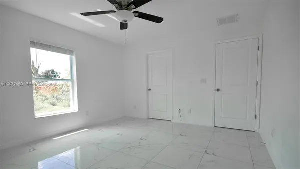 an empty room with white walls and ceiling fan