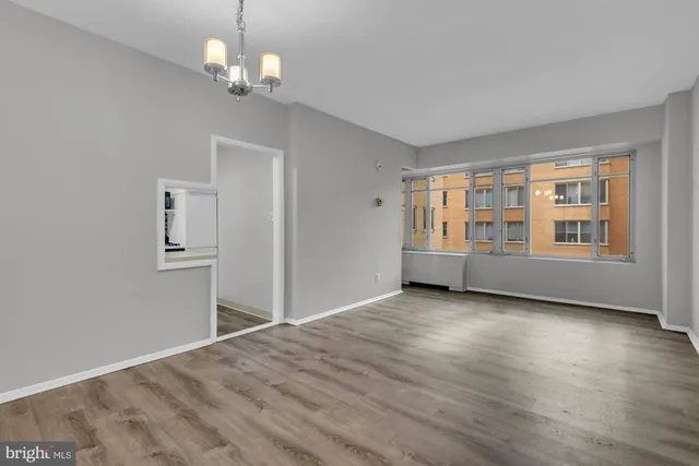a view of an empty room with a window and wooden floor