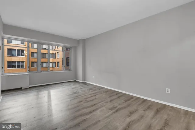 a view of an empty room with window and wooden floor