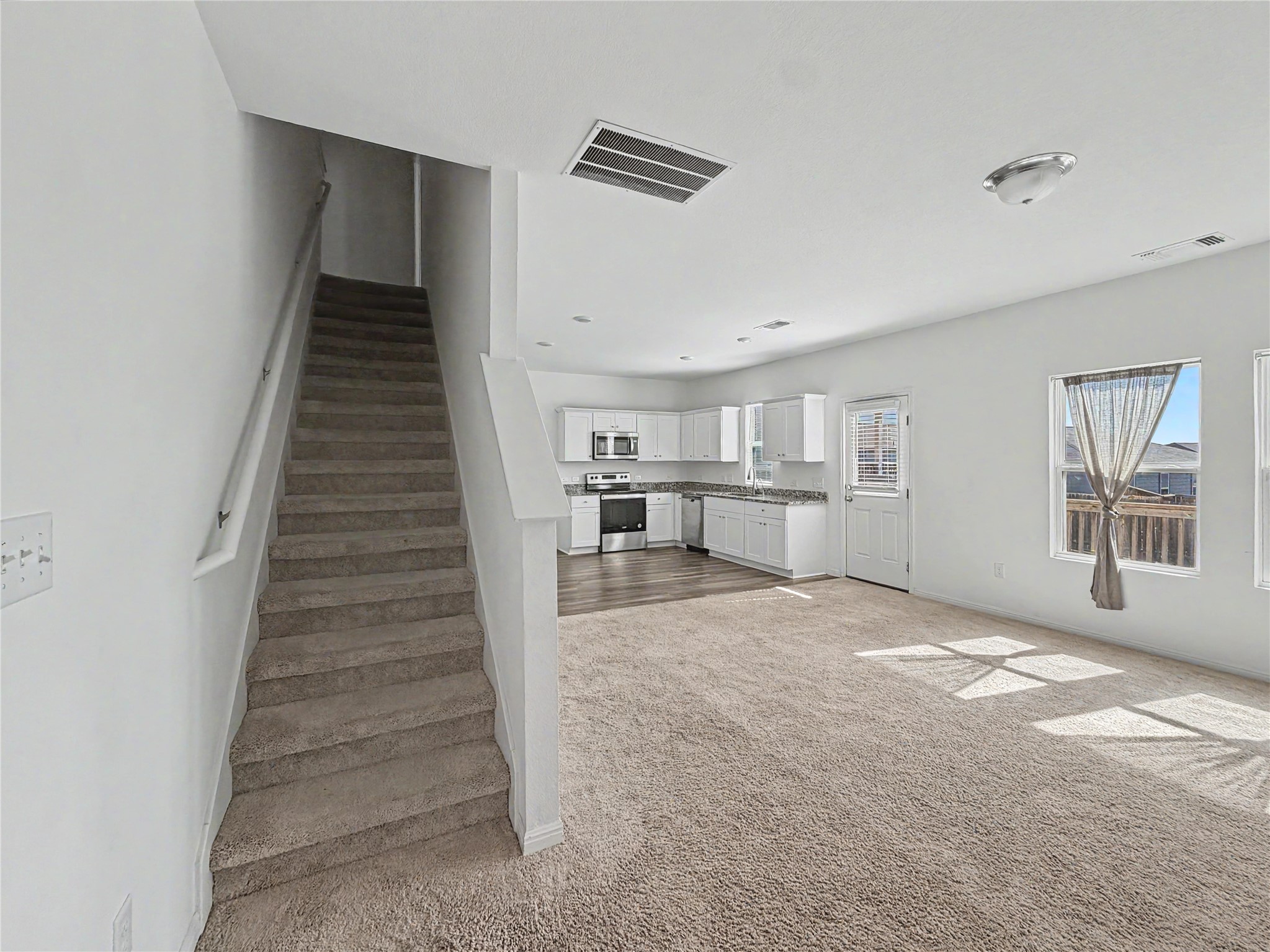 229 Night Riders Way Jarrell, TX 76537 - Photo 18 of 19 An open floorplan seamlessly connects the carpeted living area to the kitchen and staircase.