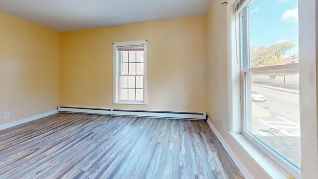 a view of an empty room with wooden floor and a window