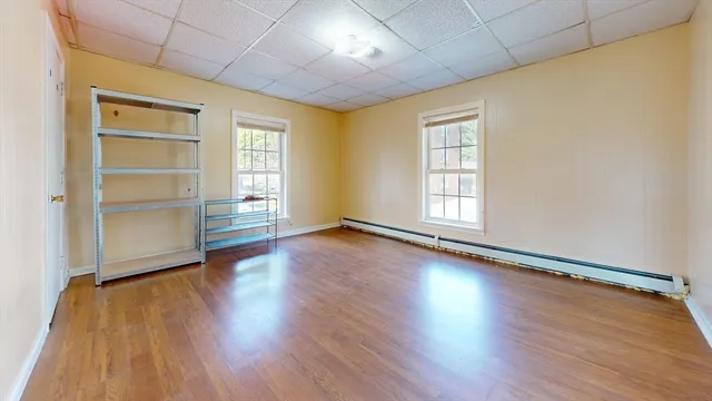 an empty room with wooden floor closet and windows