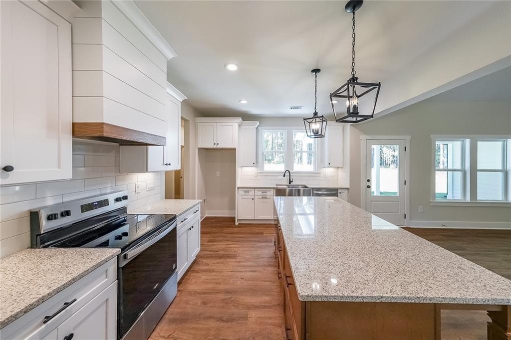 3300 Holly Springs Road Rockmart, GA 30153 - Photo 17 of 38 a large kitchen with stainless steel appliances granite countertop a sink a stove and a wooden floors