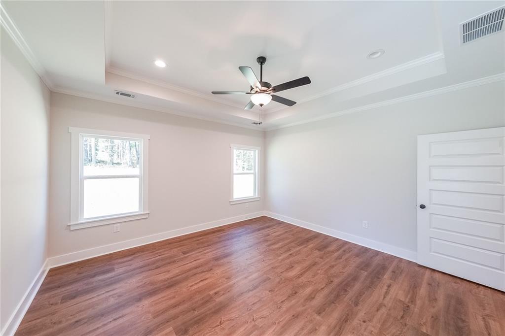 3300 Holly Springs Road Rockmart, GA 30153 - Photo 27 of 38 an empty room with wooden floor chandelier fan and windows