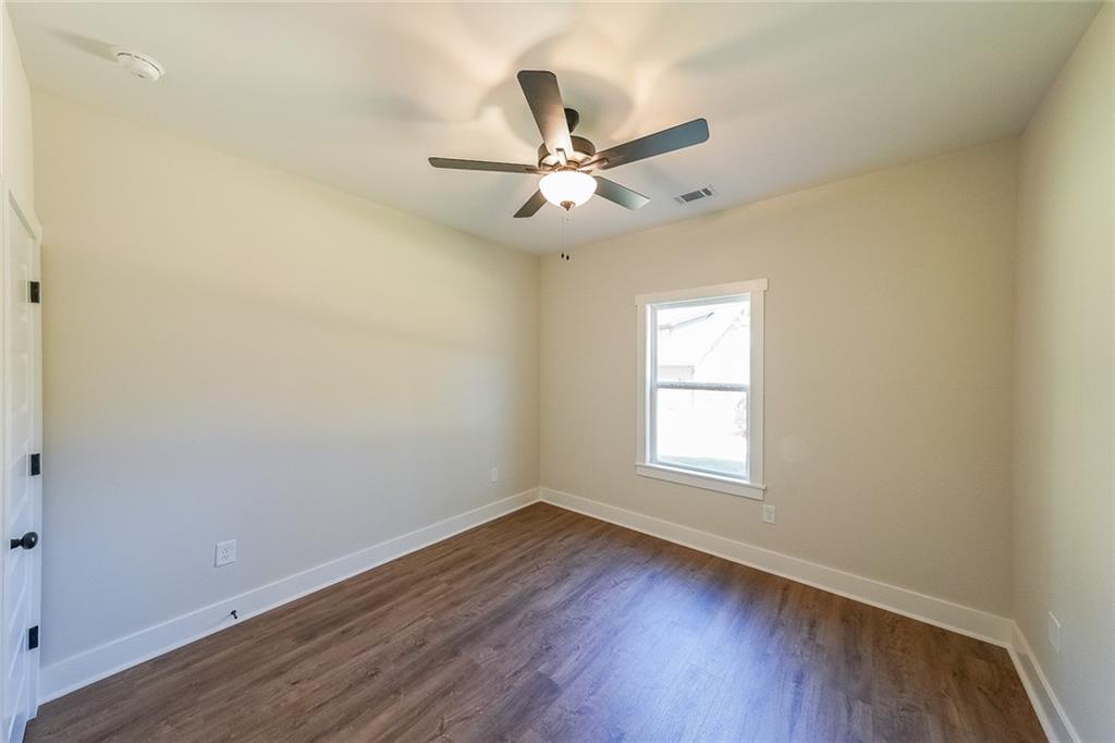 3300 Holly Springs Road Rockmart, GA 30153 - Photo 33 of 38 an empty room with wooden floor ceiling fan and windows