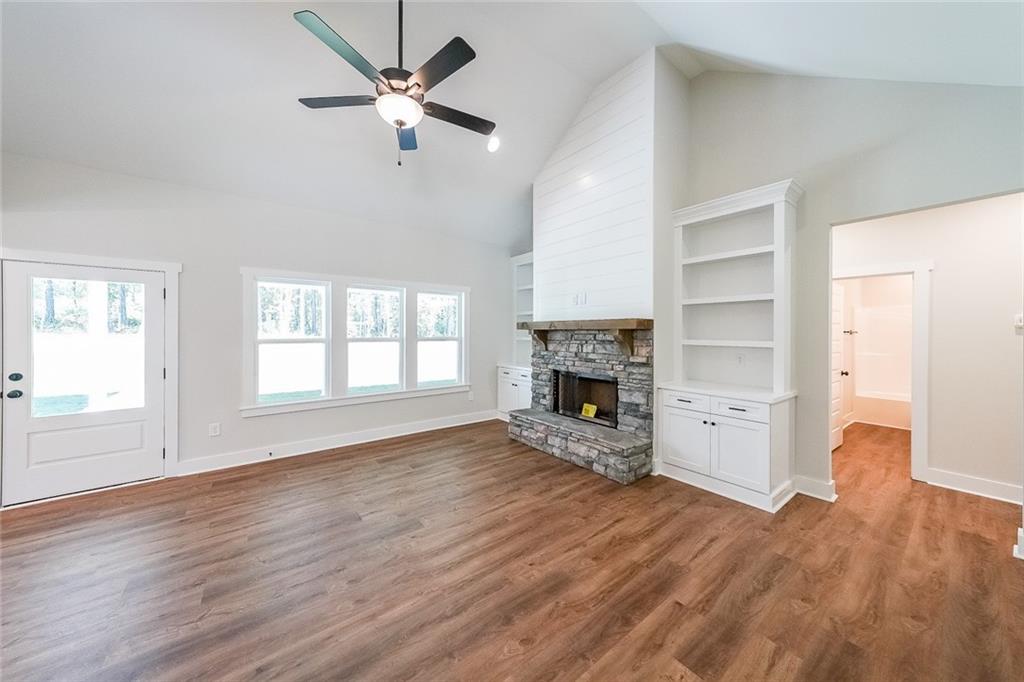 3300 Holly Springs Road Rockmart, GA 30153 - Photo 8 of 38 an empty room with wooden floor a ceiling fan and a fireplace