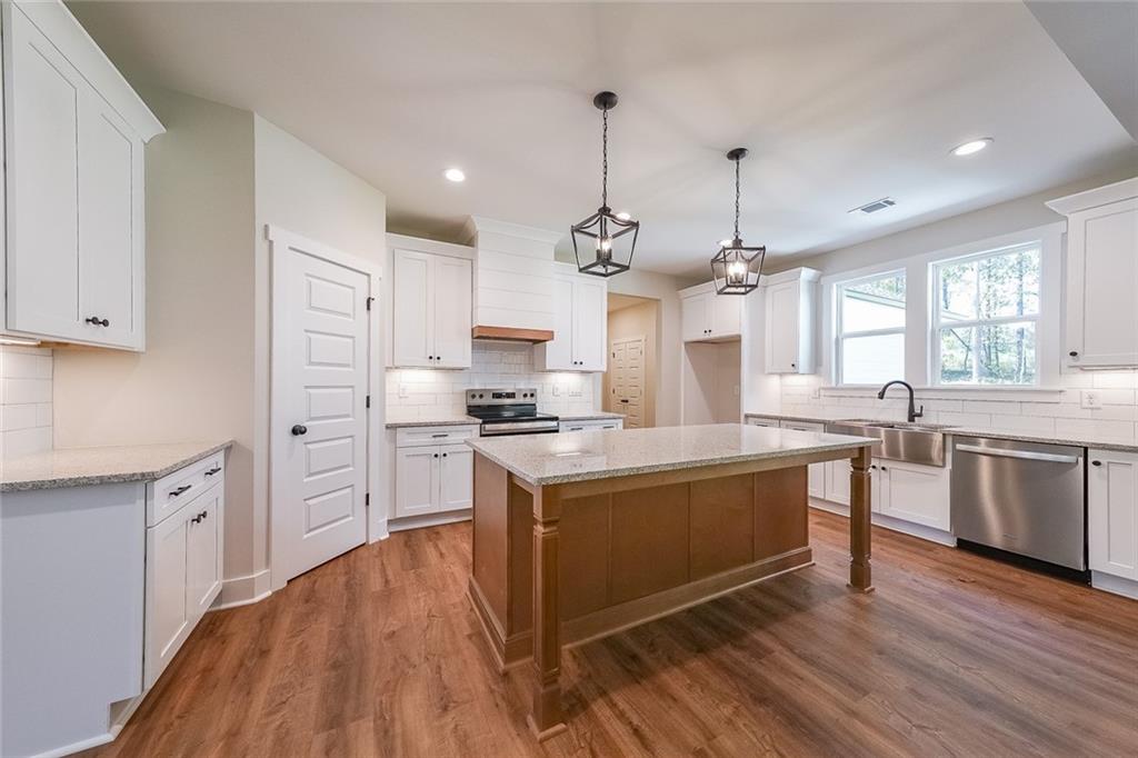 3300 Holly Springs Road Rockmart, GA 30153 - Photo 10 of 38 a large kitchen with stainless steel appliances granite countertop a stove a sink dishwasher a refrigerator white cabinets wooden floor and a fireplace