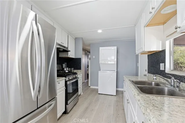 a kitchen with stainless steel appliances granite countertop a refrigerator a stove a sink and a window