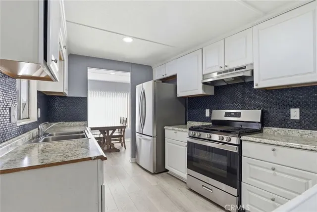 a kitchen with stainless steel appliances granite countertop a stove a refrigerator and a sink