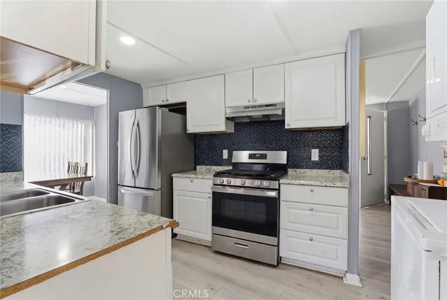 a kitchen with stainless steel appliances granite countertop a refrigerator stove and white cabinets