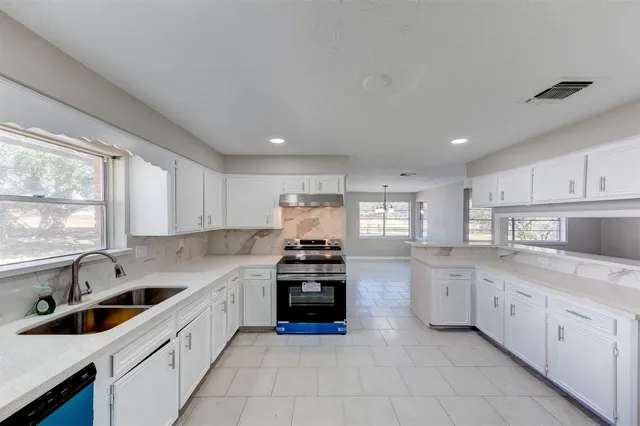 a kitchen with granite countertop white cabinets and stainless steel appliances