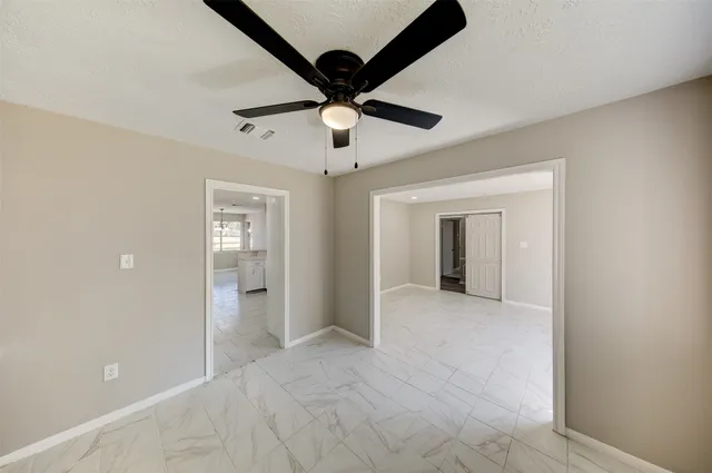 a view of an empty room and chandelier fan