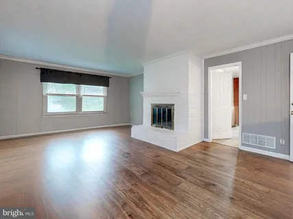 an empty room with wooden floor fireplace and windows