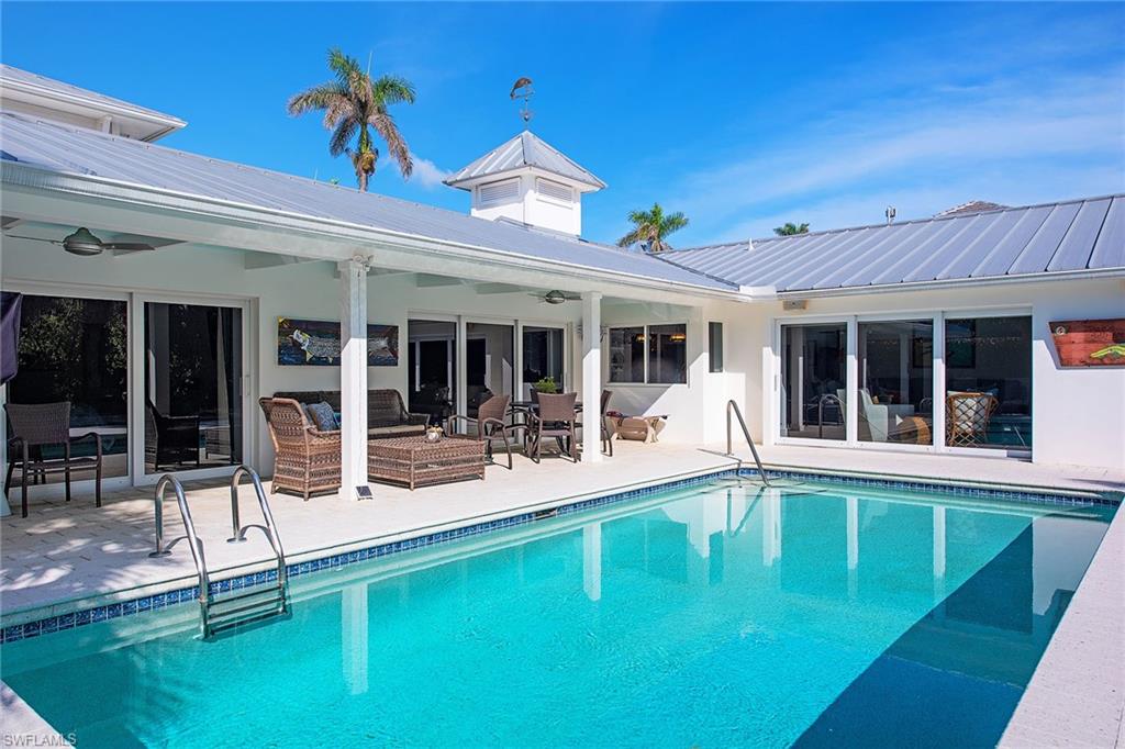 370 Rudder Road Naples, FL 34102 - Photo 19 of 26 a front view of a house with swimming pool and porch with furniture