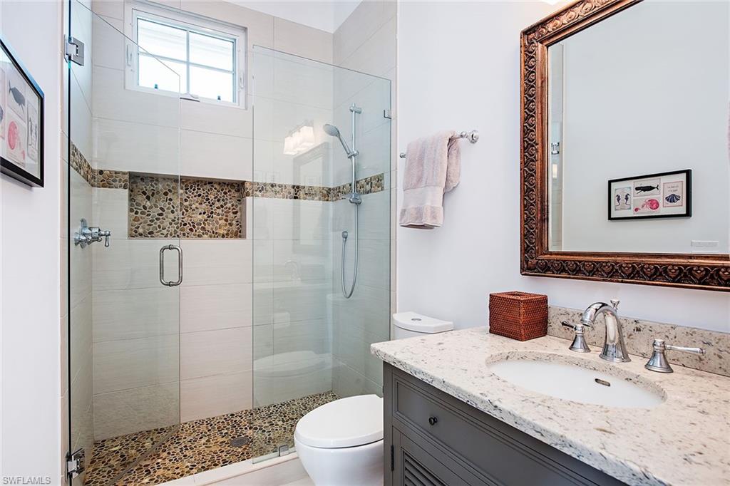 370 Rudder Road Naples, FL 34102 - Photo 21 of 26 a bathroom with a granite countertop sink a toilet a shower and a mirror