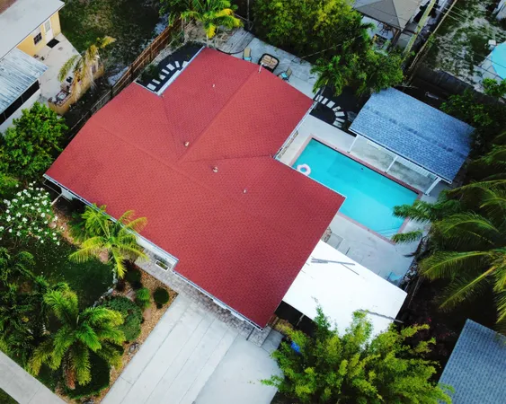 an aerial view of a red and white house with a yard and plants