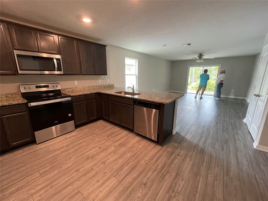 77444 Lumber Creek Boulevard Yulee, FL 32097 - Photo 5 of 24 a kitchen with stainless steel appliances granite countertop hardwood floor sink stove dining table and chairs