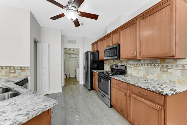 a kitchen with granite countertop a sink a counter top space appliances and cabinets