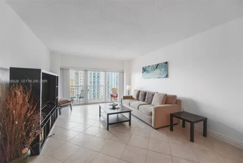 a living room with furniture a flat screen tv and a refrigerator