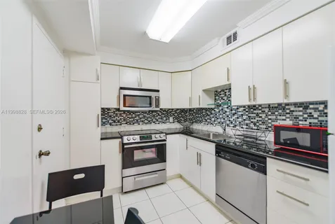 a kitchen with granite countertop white cabinets and stainless steel appliances